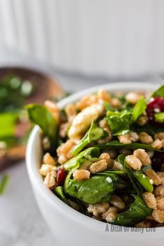 a white bowl filled with green vegetables and nuts