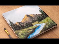 a painting on a wooden table with a brush and watercolor pencils next to it