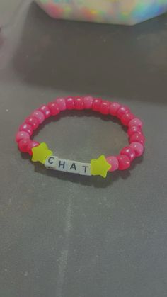 a pink bracelet with yellow stars and the word chat written in white letters on it