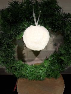 a green wreath with a white ornament hanging from it's center piece