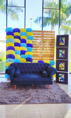 a blue couch sitting on top of a rug in front of a wall filled with paper fans