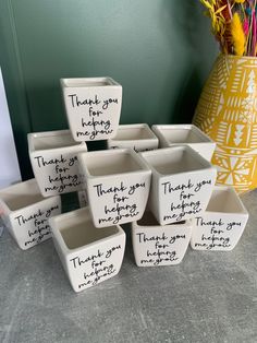 a group of white bowls with writing on them sitting next to a vase filled with flowers