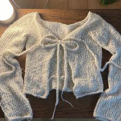 a white sweater on a wooden table next to a lamp