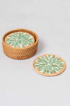 two wicker trays with green and white designs on the lids, one is round