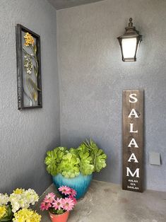 two vases filled with flowers sitting next to a sign that says salam on it