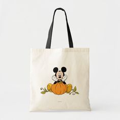 a mickey mouse sitting on top of a pumpkin tote bag with an image of the character