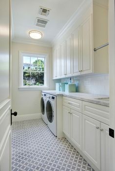 a washer and dryer in a white kitchen with blue floor tiles on the floor