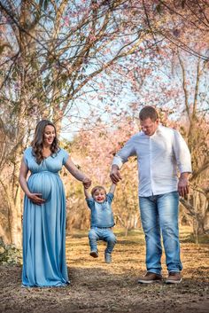 a man and woman holding the hand of a baby boy