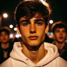 a young man wearing a white hoodie in the dark