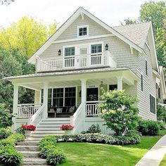 a white house with steps leading up to the front door and covered in flowers on the lawn