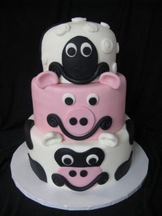 a three tiered cake decorated with black and pink fondant animals on it's sides