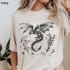 Romantasy Reader Dragon T-Shirt Pressed Wildflowers and Dragons Shirt Retro Design, Comfort Colors  🌸 Step into a world of magic with our unique T-shirt, featuring a majestic dragon and ancient parchment letter graphic, adorned with dried pressed wildflowers.  💖 Ideal for casual wear or as a standout piece, each shirt is a blend of art and nature, ensuring you feel stylish and connected to the earth.  ☛ DESCRIPTION: --Comfort Colors Shirts are made with medium weight fabric. --100% ring spun U Dragon Outfit Aesthetic, Dragon Outfit, Pressed Wildflowers, Majestic Dragon, T Shirt Press, Dragons Clothes, Dragon Shirt, Hoodie Aesthetic, Book Dragon