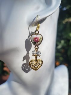 "These pretty double gold heart earrings are brand new and made by me. Two extra sparkle ball charms add a bit of shimmer to the piece. All aspects of the earrings are gold plated over alloy metal. Middle piece is rose gold plated.  Leverback attachment.  Measures just about 2\" in length. Made with love." Rose Gold Plated Heart Drop Earrings, Dainty Metal Earrings For Valentine's Day, Valentine's Day Dangling Charms Drop Earrings, Rose Gold Heart Charm Drop Earrings, Rose Gold Heart Charm Earrings For Valentine's Day, Gold Metal Earrings With Heart Charm, Rose Gold Heart Charm Earrings For Mother's Day, Rose Gold Double Heart Earrings With Heart Charm, Rose Gold Drop Earrings With Heart Charm