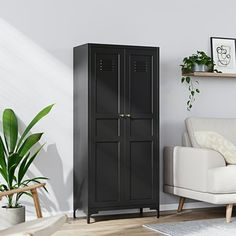 a living room with a white couch and black cabinet in the corner next to a potted plant