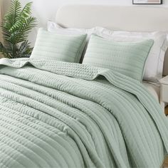 a bed with a green comforter and pillows