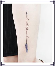 an arrow tattoo on the back of a woman's left arm with words written in cursive writing