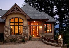 a stone house with large windows and lights on the front door is lit up at night