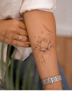 a woman's arm with a flower tattoo on the left side of her arm