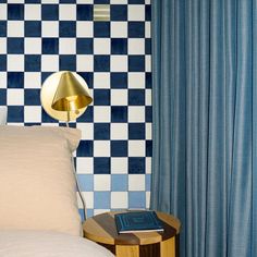 a blue and white checkered wall in a bedroom with a lamp on the end table