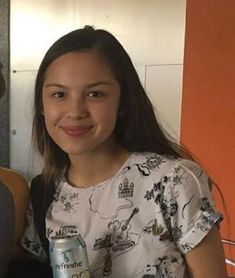 two people standing next to each other holding cans of soda and smiling at the camera