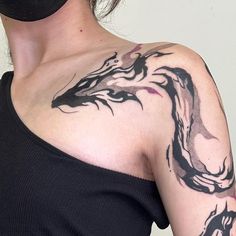 a woman with a black mask on her face has a dragon tattoo on her shoulder