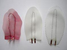 three pieces of fabric with pins attached to them, one being white and the other is pink