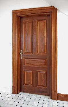 an open wooden door in the corner of a room with tile flooring and white walls