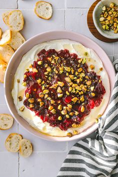 a bowl filled with whipped cream and fruit toppings next to crackers on the side