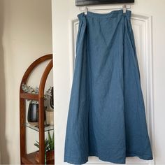 a blue skirt hanging on the wall next to a shelf with potted plants in it