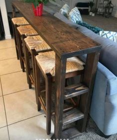 a long table with stools on top of it in a living room next to a couch