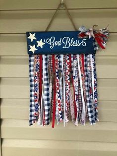 a patriotic sign hanging from the side of a house with ribbons attached to it's sides