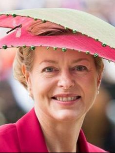 a woman wearing a pink hat with green beads on it's brims