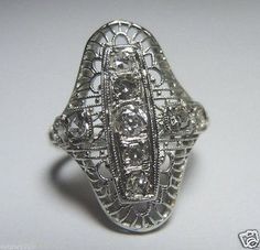 an antique silver ring with filigrees and diamonds on the front, sitting on a white surface