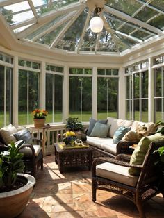 a sun room with lots of windows and furniture in the center, surrounded by potted plants