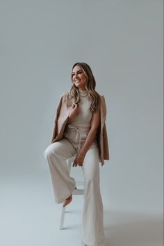 a woman is sitting on a chair and posing for the camera with her hands in her pockets