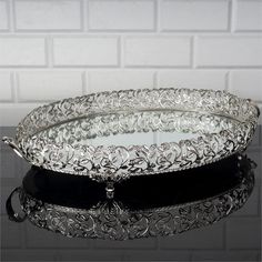 two silver serving trays sitting on top of a black table next to a white brick wall