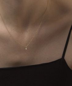 a woman wearing a necklace with a diamond on it