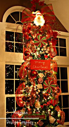 a christmas tree decorated with candy canes and candies in front of a window