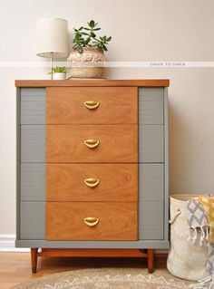 a chest of drawers sitting on top of a wooden floor next to a lamp and potted plant