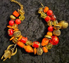 You will fall in love with this oversized bold, chunky, wild & exotic tribal red-orange statement necklace. This double strand beauty features Tibetan red resin and brass beads, copper and gold metal rondelles, a Tibetan Resin bead, African zebu* cow beads, African wood and zebu* cow bone beads, yellow, orange and red lucite cubes, red magnesite, African lost wax brass, red branch coral nuggets, Yoruba brass, Tibetan brass bells and a rare Ashanti brass mask. Adjusts from 17-20" with a 3" extender chain. Gold tone hardware and a hook clasp. Best for smaller necks. A haute couture African - Tibetan statement piece from the Atelier of Kat Kouture. **The bone used in this piece is from African domesticated cattle know as Zebu. They are not an endangered species nor do they produce any protect Orange Statement Necklace, Rocker Chic Accessories, Cow Bones, Statement Bib Necklace, Unique Pendant Necklace, Yellow Jewelry, Brass Bells, Mermaid Necklace, Bone Beads