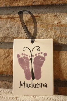 a ceramic ornament with the name and image of a baby's feet