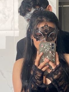 a woman taking a selfie in front of a mirror wearing a mask and holding a cell phone