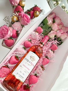 a bottle of wine in a box with pink flowers on the table next to it