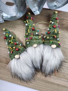 two furry christmas trees on top of a wooden table next to some metal bells and chains