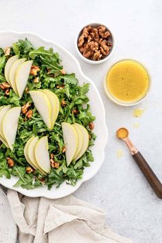 a salad with apples, walnuts and dressing on a white plate