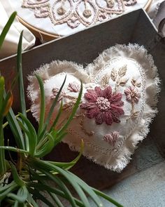 a heart shaped pillow sitting on top of a wooden box next to plants and other items