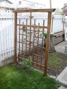 a wooden trellis in the middle of a yard