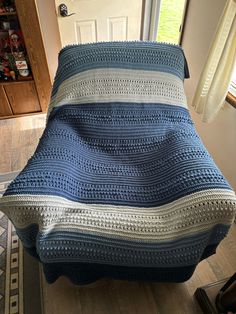 a blue and white crocheted blanket sitting on top of a bed next to a door