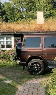 a brown jeep parked in front of a house with grass on top of the roof