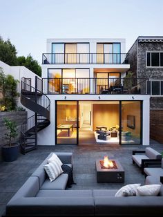 an outdoor living area with couches, fire pit and stairs leading to the upper floor